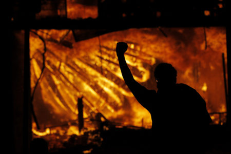 A protester gestures in front of the burning 3rd Precinct building of the Minneapolis Police Department.